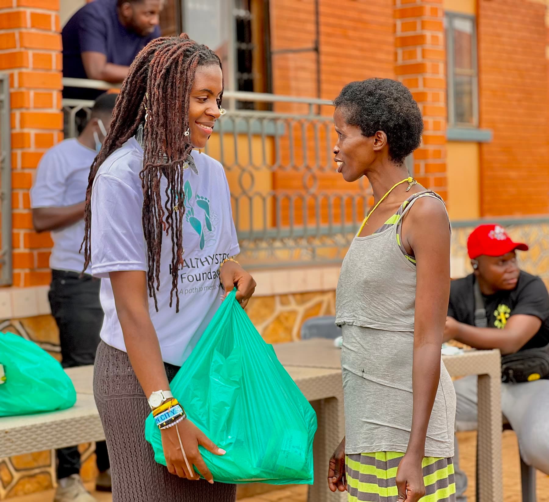 A Healthy Steps volunteer speaking warmly with a woman receiving a food package